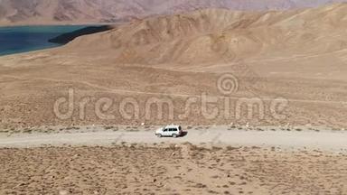 在4x4路的一侧，汽车沿着砾石小径驶向干旱山区的湖泊。 帕米尔公路丝绸之路
